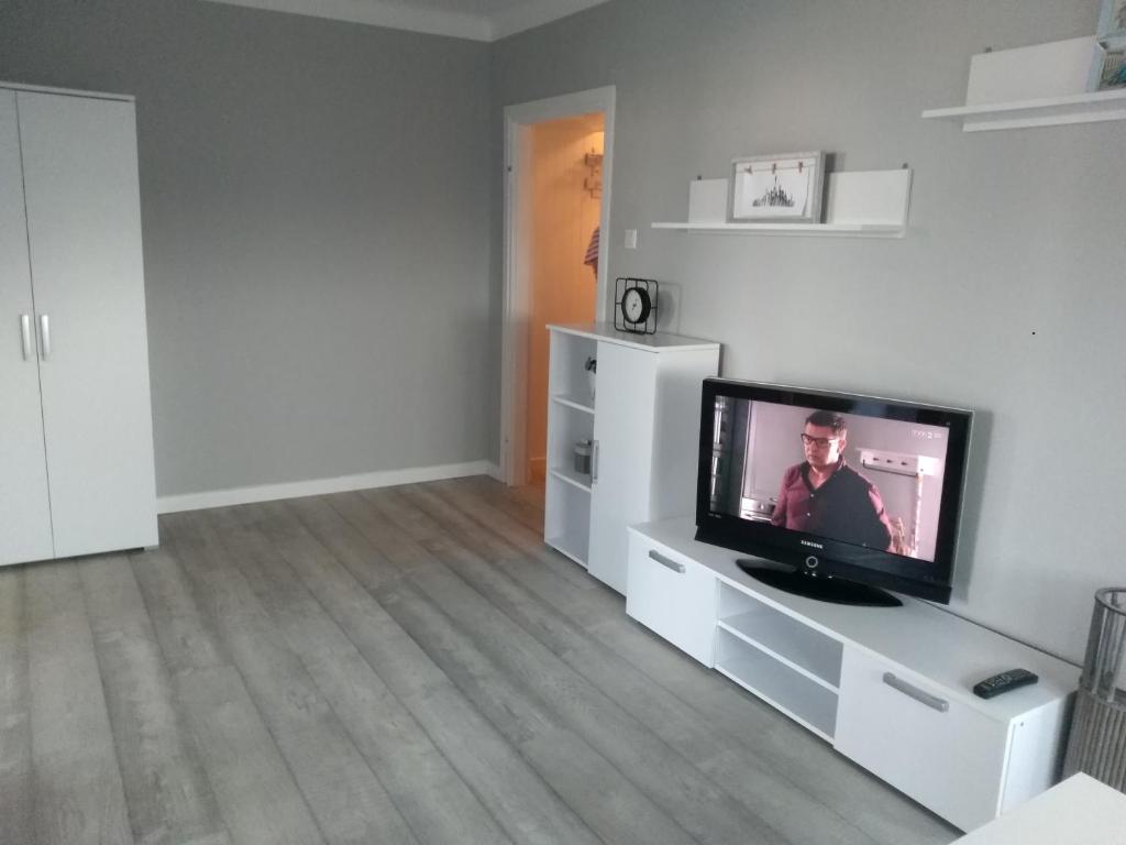 una sala de estar con TV en un centro de entretenimiento blanco en Apartament Centrum, en Radom