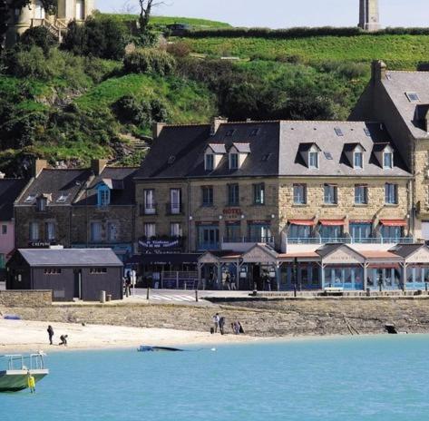 a large building on the beach next to the water at La Mere Champlain in Cancale