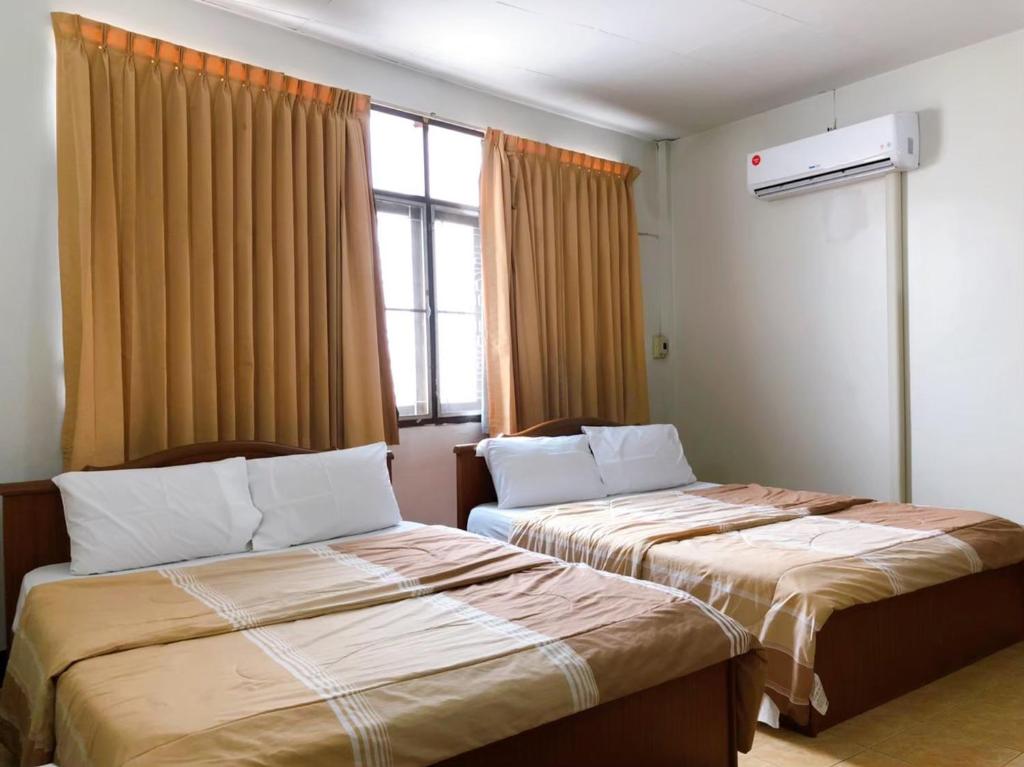2 camas en una habitación de hotel con ventana en Tokyo Hotel, en Nakhon Ratchasima