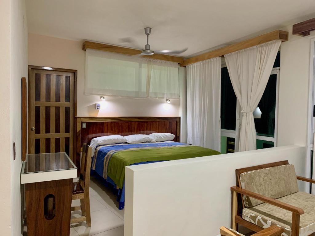 um quarto com uma cama, uma mesa e uma cadeira em Lidxi Rosae em Puerto Escondido