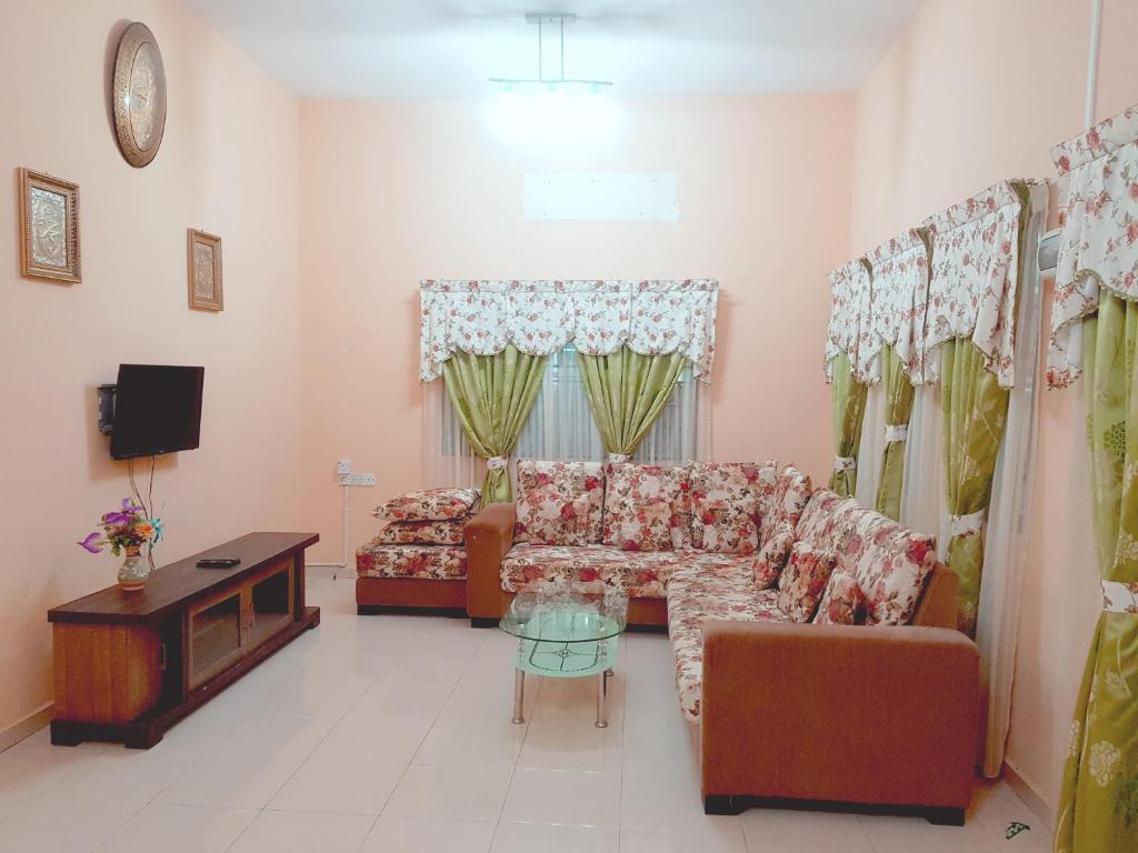 Kembara Homestay Lenggong في Kampong Ulu Jepai: غرفة معيشة مع أريكة وطاولة