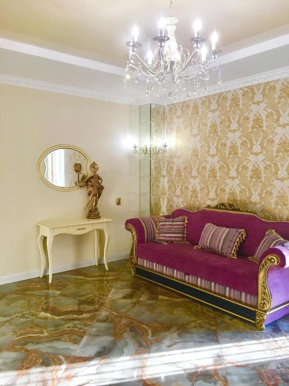 sala de estar con sofá púrpura y espejo en Люкс в Жмеринке, en Zhmerynka