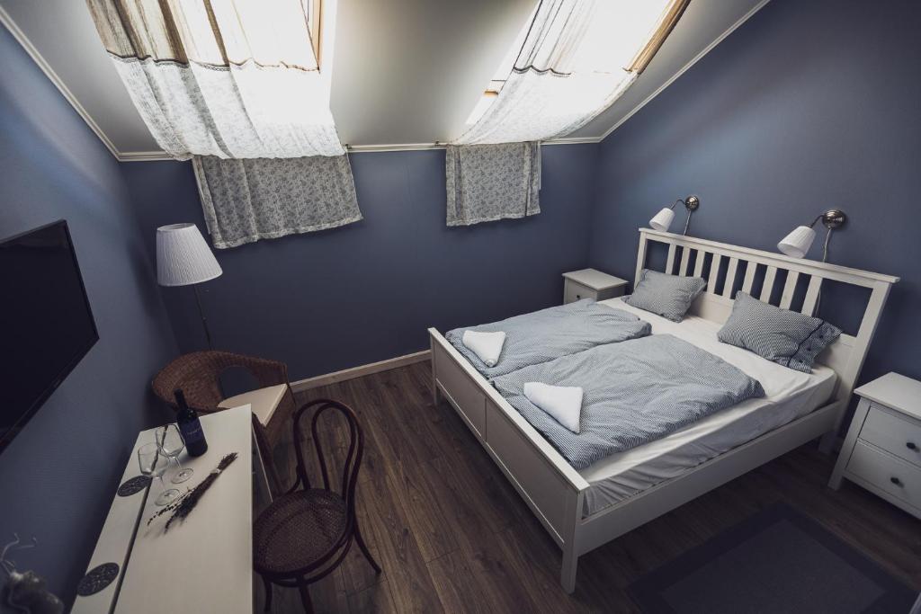 sypialnia z łóżkiem z niebieskimi ścianami i oknami w obiekcie Kerámia - Vendégszobák w mieście Szekszárd