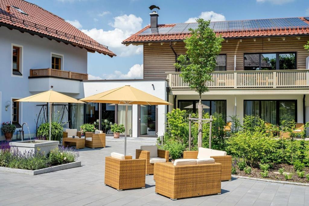 a patio with chairs and umbrellas in front of a building at Landhaus Tanner in Waging am See