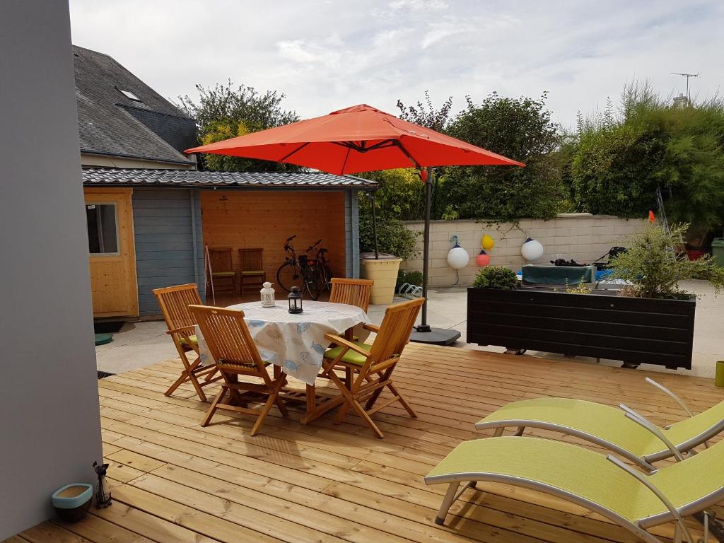 un patio con mesa, sillas y sombrilla en Appart 2 personnes proche plage de la Fresnaye, en Saint-Cast-le-Guildo