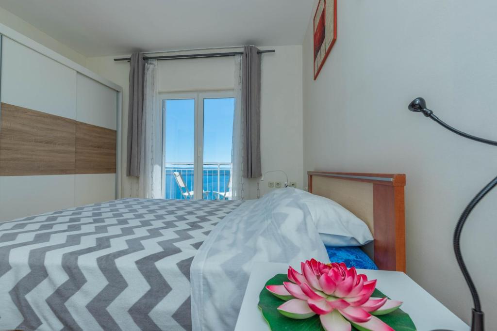 - une chambre avec un lit et une table fleurie dans l'établissement Apartman Zlatica, à Dramalj