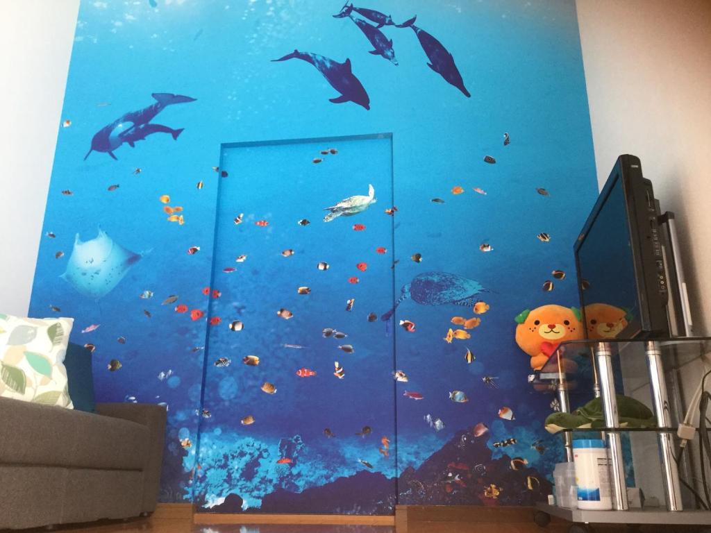 a bedroom with a blue wall with dolphins and fish at 民泊大森 in Iyo