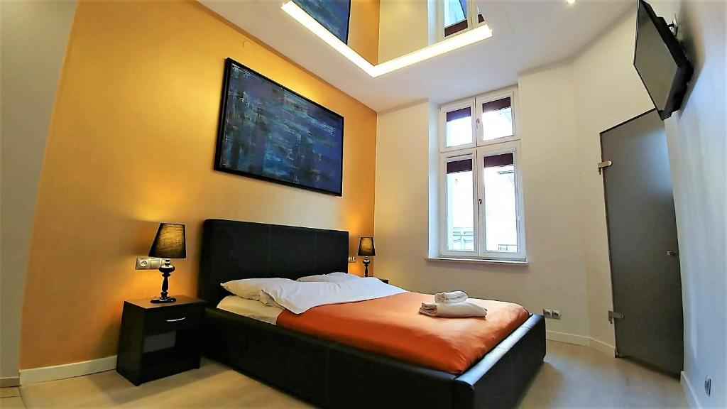 een slaapkamer met een bed en een tv aan de muur bij Mirror Gold & Grey Studios in Krakau