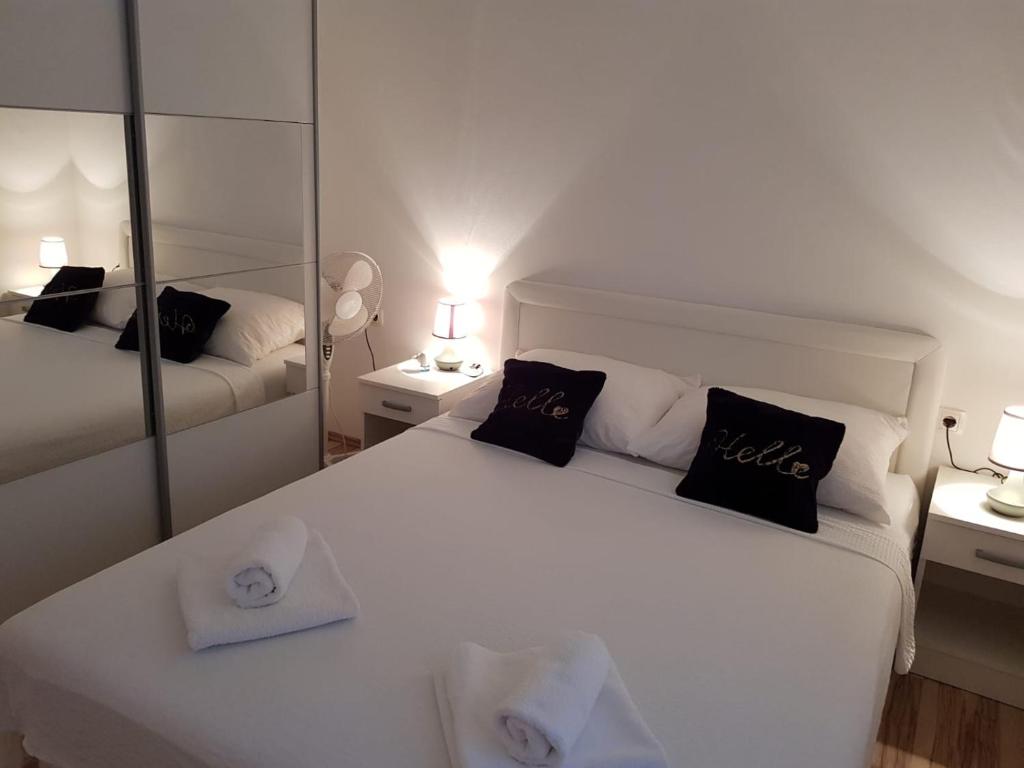 1 dormitorio con 1 cama blanca grande y espejo en Apartman Andrea en Zadar