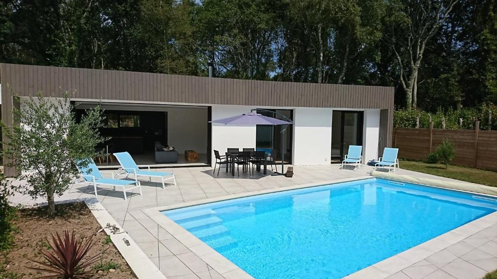 a swimming pool with chairs and a table and an umbrella at Villa Gavrinis in Ploemel