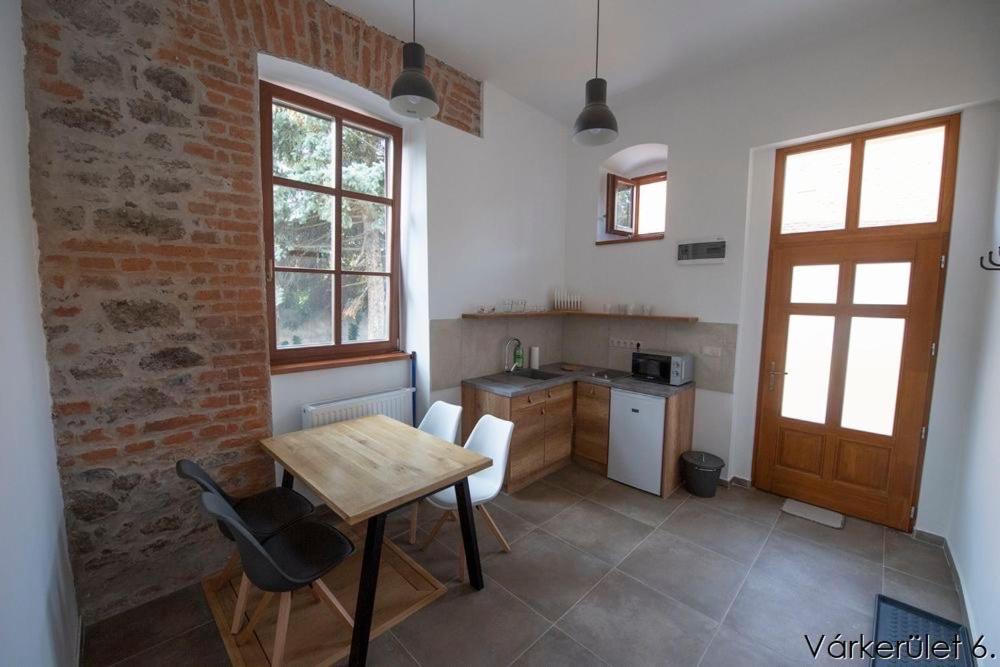 a kitchen with a wooden table and a kitchen with a counter at Várkerület 6 Apartman in Sárvár