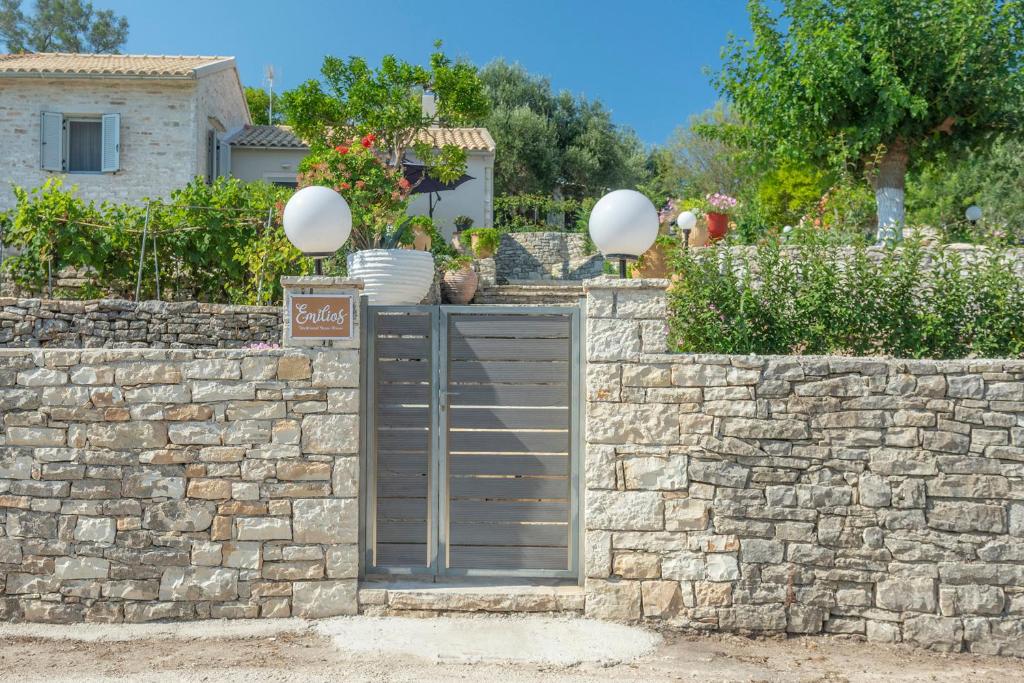 a stone fence with a gate in front of a house at Emilios Stone House in Gaios
