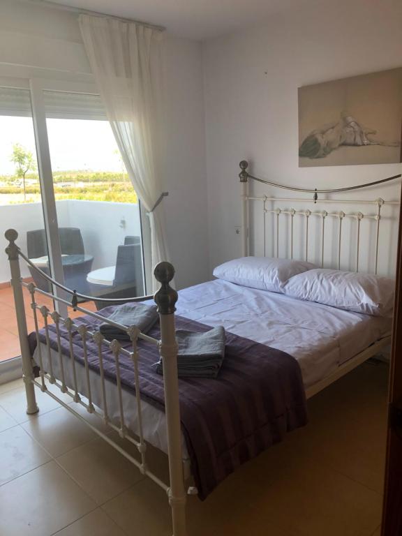1 dormitorio con cama y vistas a un balcón en Condado de Alhama, en Alhama de Murcia
