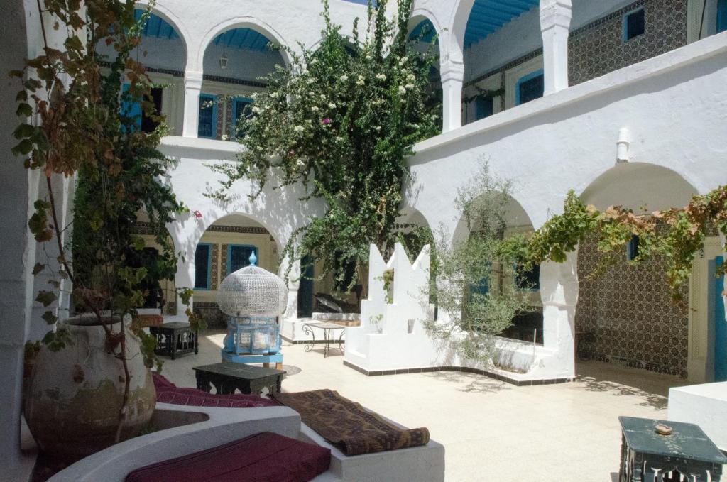 une cour dans un bâtiment avec des arbres et des tables dans l'établissement Hôtel Djerba Erriadh, à Houmt Souk