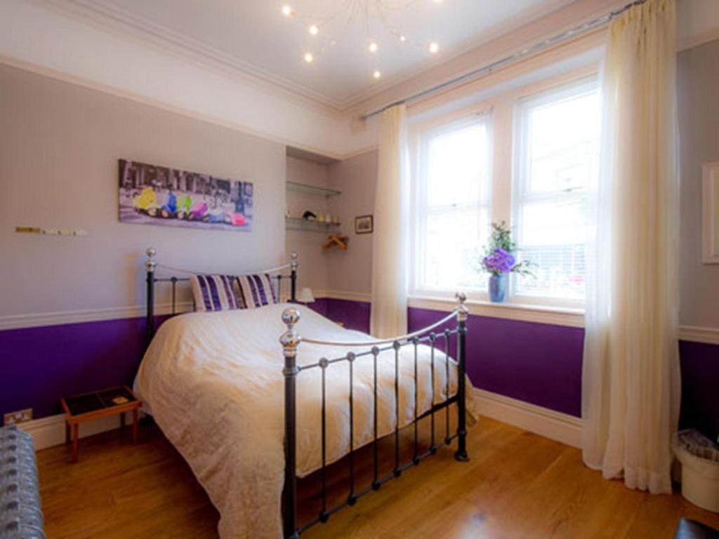 a bedroom with a bed with purple walls and windows at King William IV Guest House in Settle