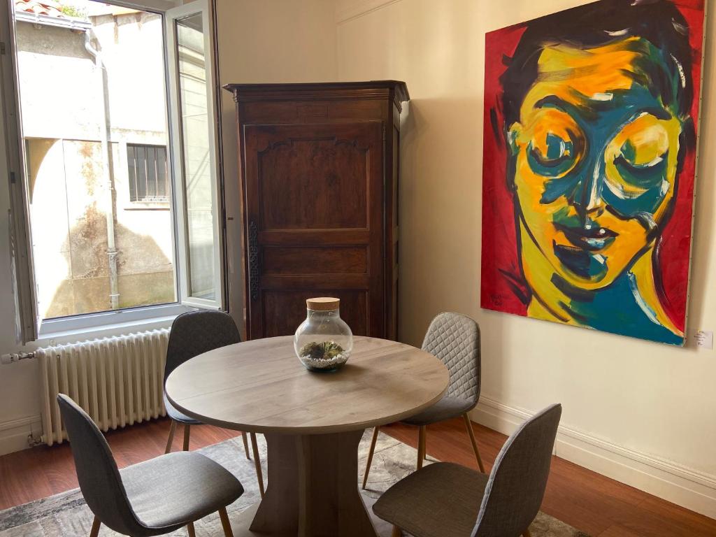 uma mesa e cadeiras num quarto com uma pintura em La Villa B em Cholet