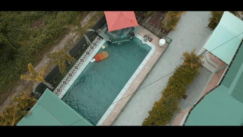 - une vue sur la piscine dotée d'un parasol rouge dans l'établissement Verveine, à Vieux Bourg