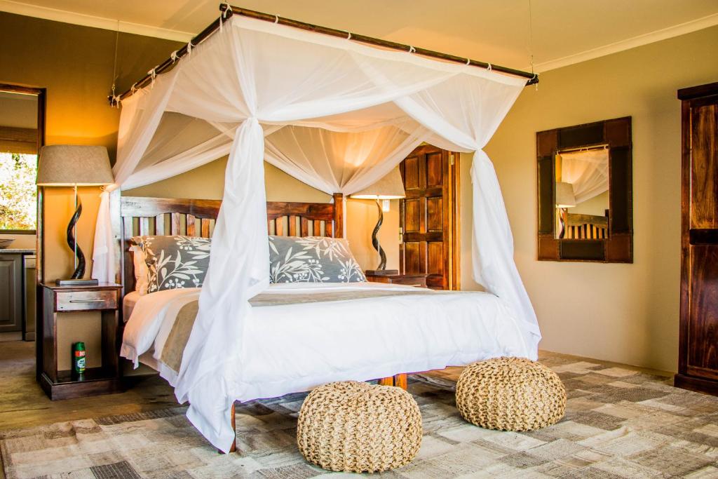 a bedroom with a canopy bed with two ottomans at African Safari Lodge in Grahamstown