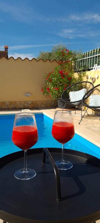 dwa kieliszki wina siedzące na stole obok basenu w obiekcie Holiday Home "Mala kuća " with heated pool w Puli