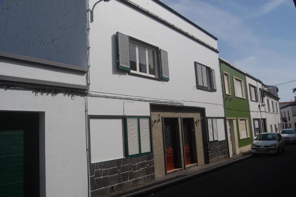 um edifício branco com janelas verdes e um carro estacionado numa rua em Quinta da Cidade em Ponta Delgada