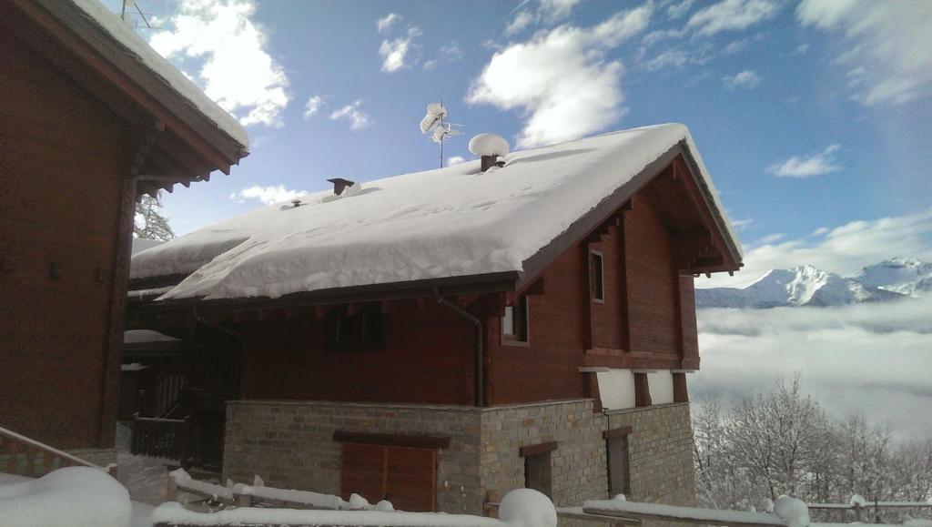 un techo cubierto de nieve de un edificio con dos pájaros. en Villetta Piemartin, en Saint Vincent