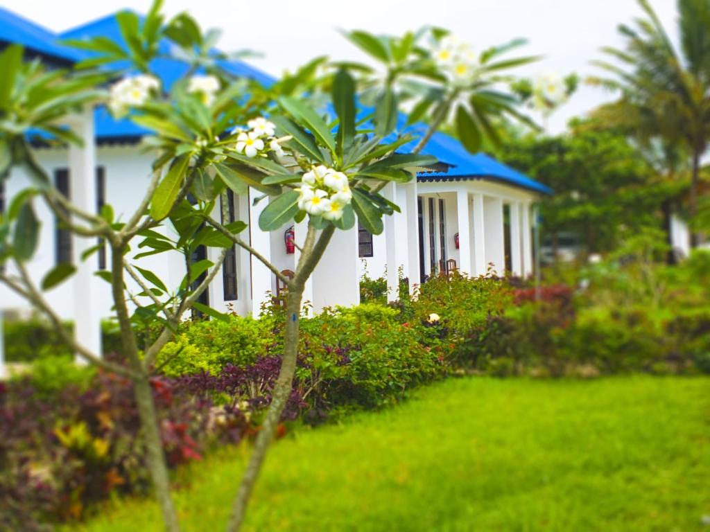 a white house with trees and flowers in front of it at Kigwedeni Villas in Nungwi