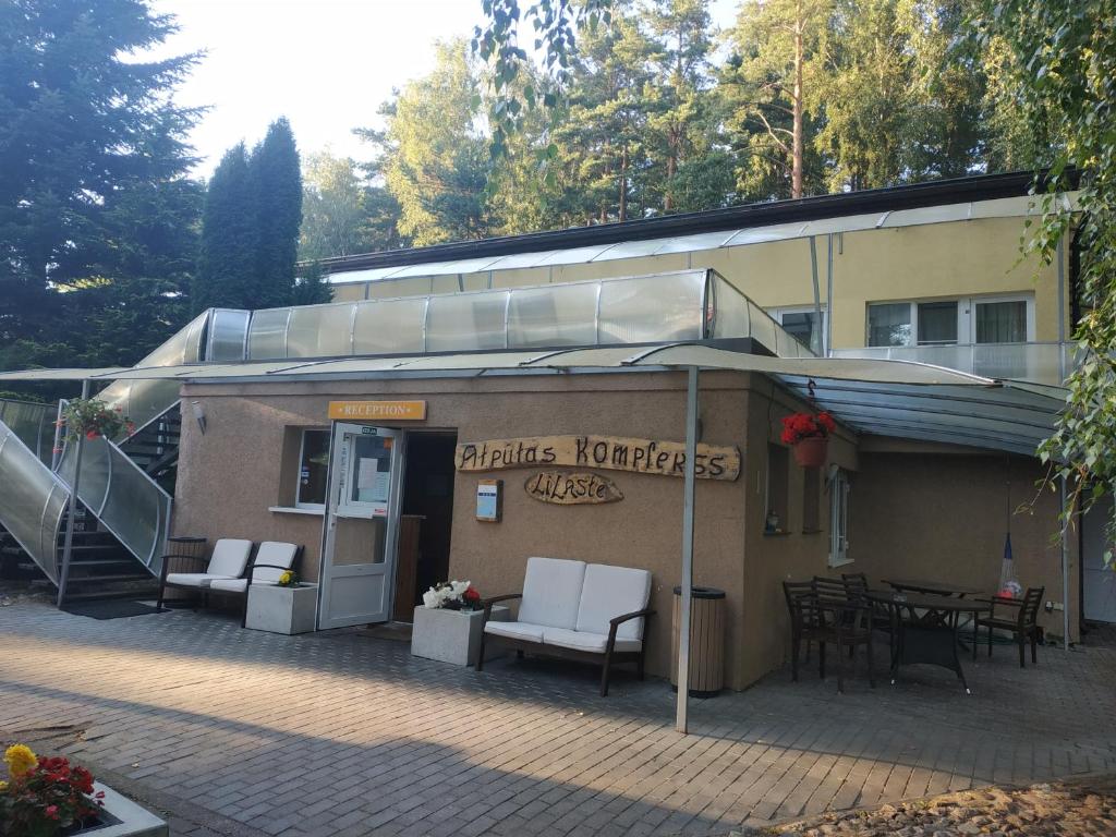 a building with a patio with white chairs and an umbrella at Atpūtas komplekss Lilaste in Lilaste