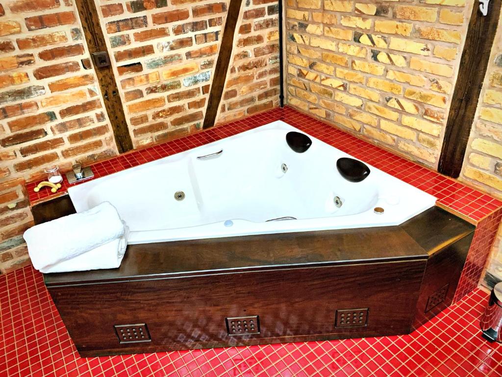 a bath tub in a room with a brick wall at Aconchegante Casa de Hospedagem Enxaimel in Timbó