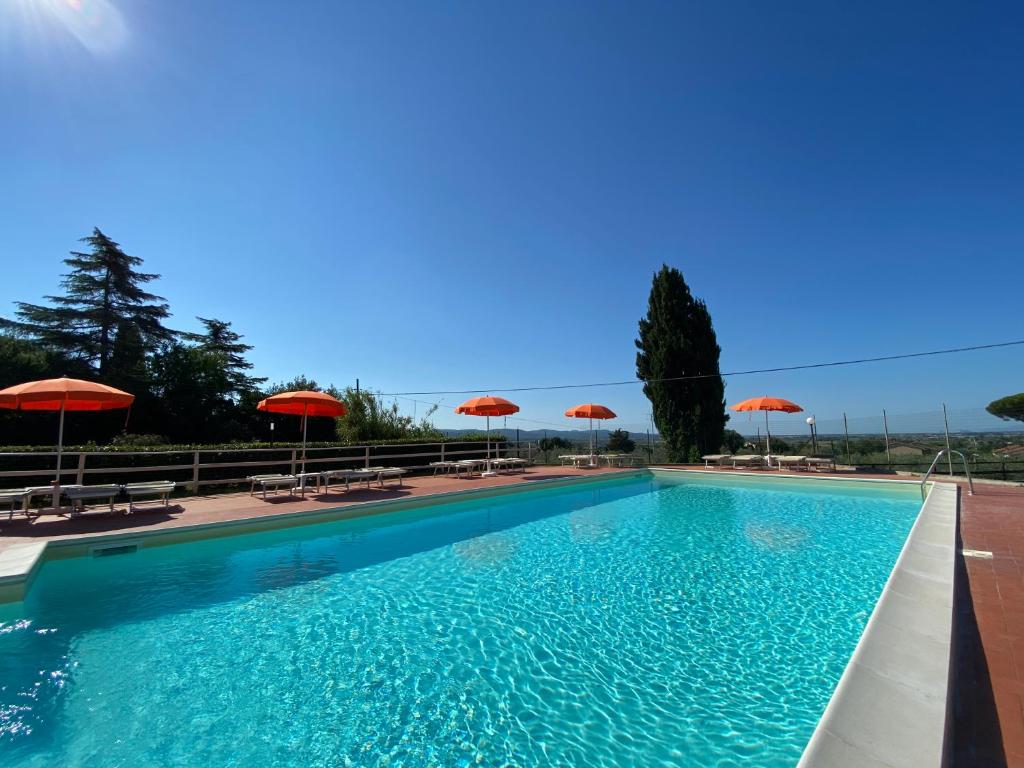 una gran piscina con sombrillas y sillas en La Fonte degli Angeli Apartments, en Suvereto