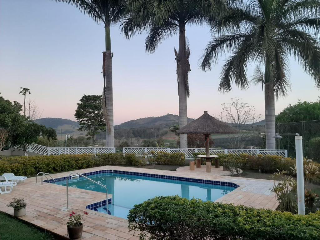 a swimming pool with palm trees in the background at Chacára da Juma-Piscina climatizada in Piracaia