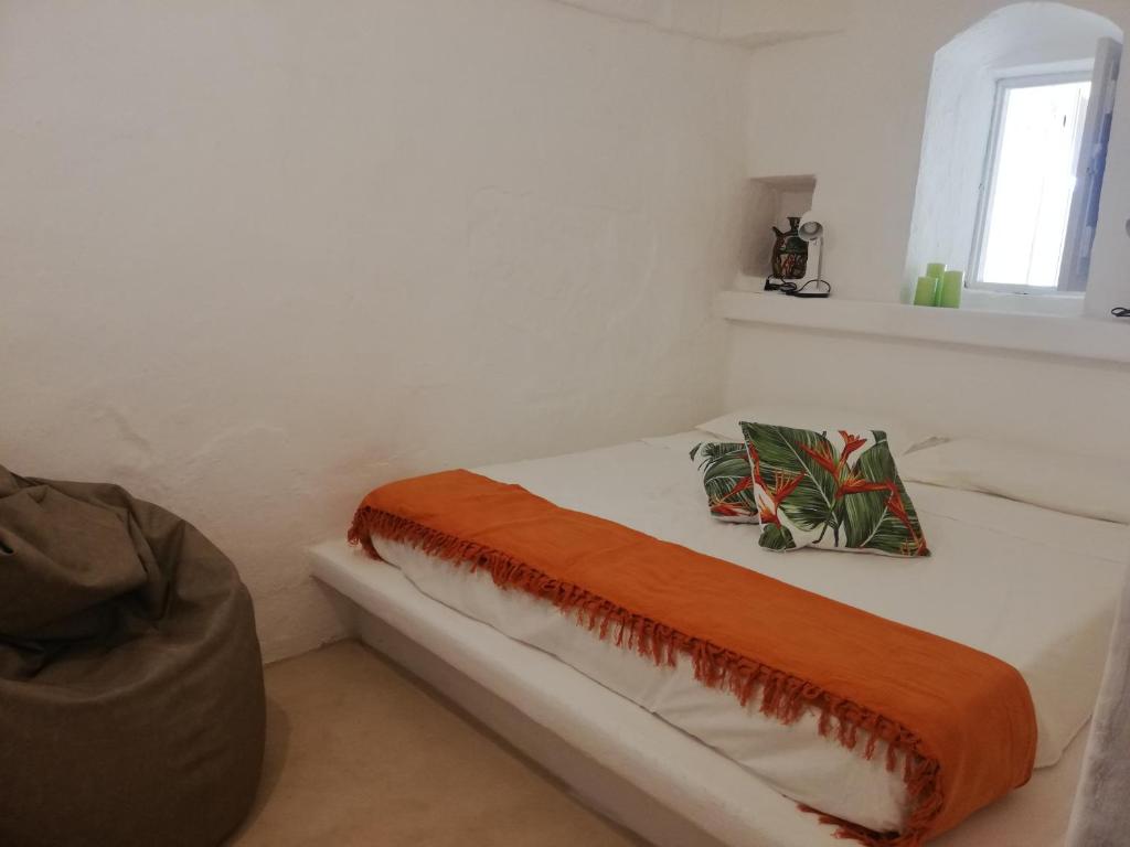 białe łóżko z pomarańczowym kocem i oknem w obiekcie Nel cuore di Ostuni w mieście Ostuni