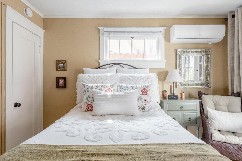 a bedroom with a white bed with pillows and a window at Casita Charm, Cozy Character in Long Beach