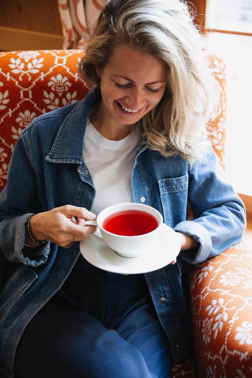 a woman sitting on a couch holding a cup of tea at Hotel Aurora in Lech am Arlberg