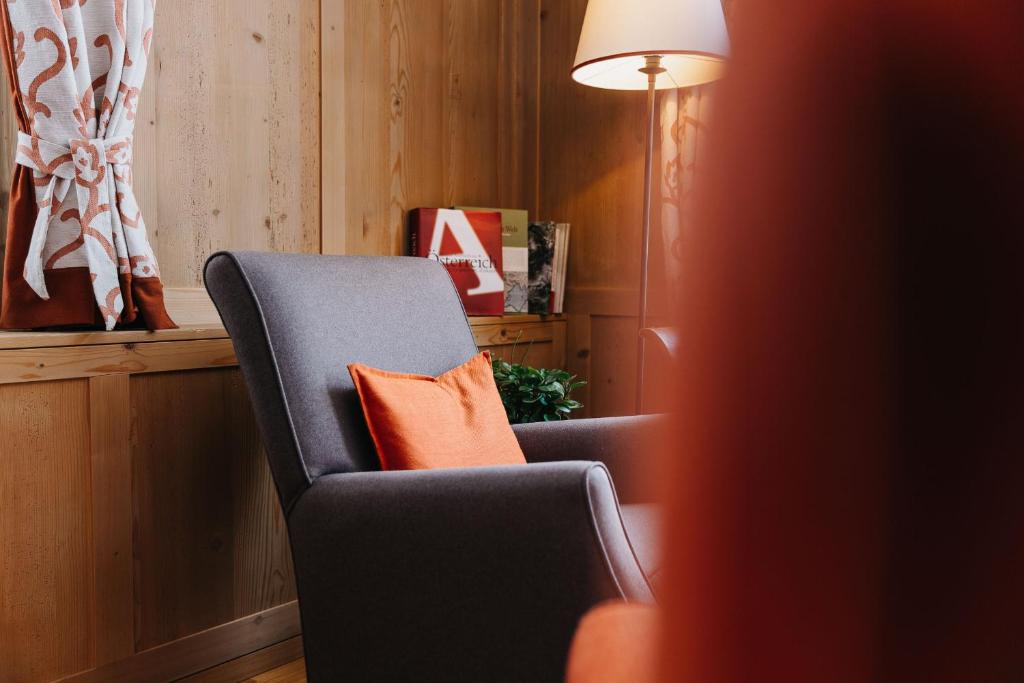 a chair with an orange pillow in a room at Hotel Aurora in Lech am Arlberg