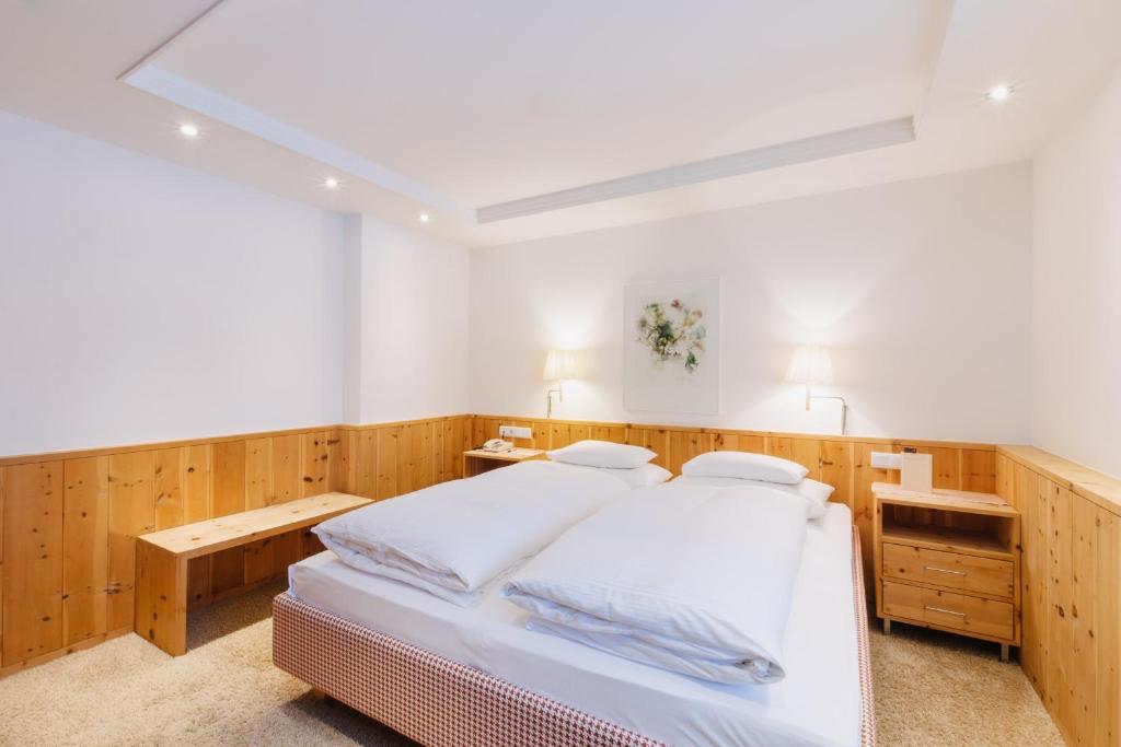 a bedroom with a white bed and wooden walls at Hotel Aurora in Lech am Arlberg