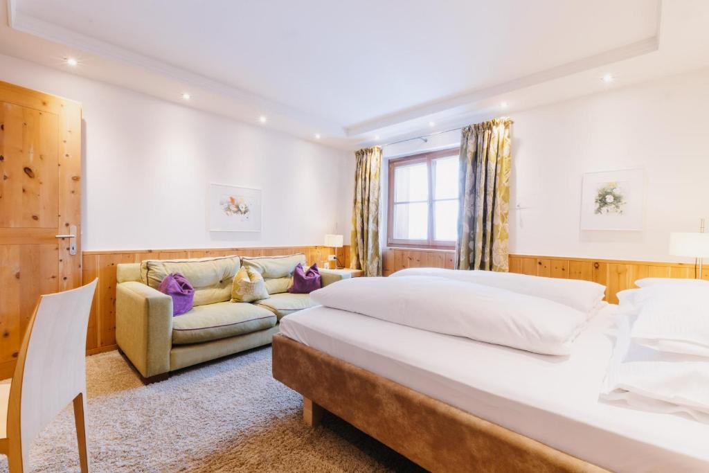 a bedroom with a large bed and a couch at Hotel Aurora in Lech am Arlberg