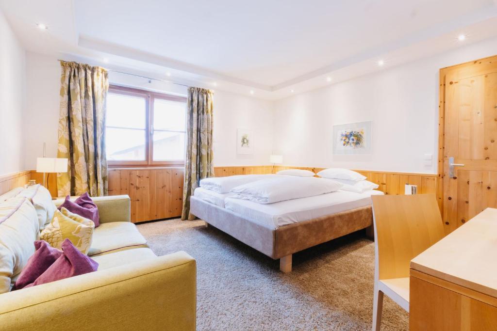 a hotel room with two beds and a couch at Hotel Aurora in Lech am Arlberg