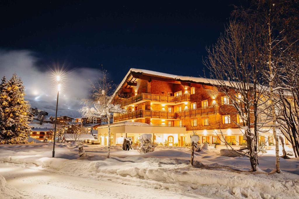 un grand bâtiment dans la neige la nuit dans l'établissement Hotel Aurora, à Lech am Arlberg