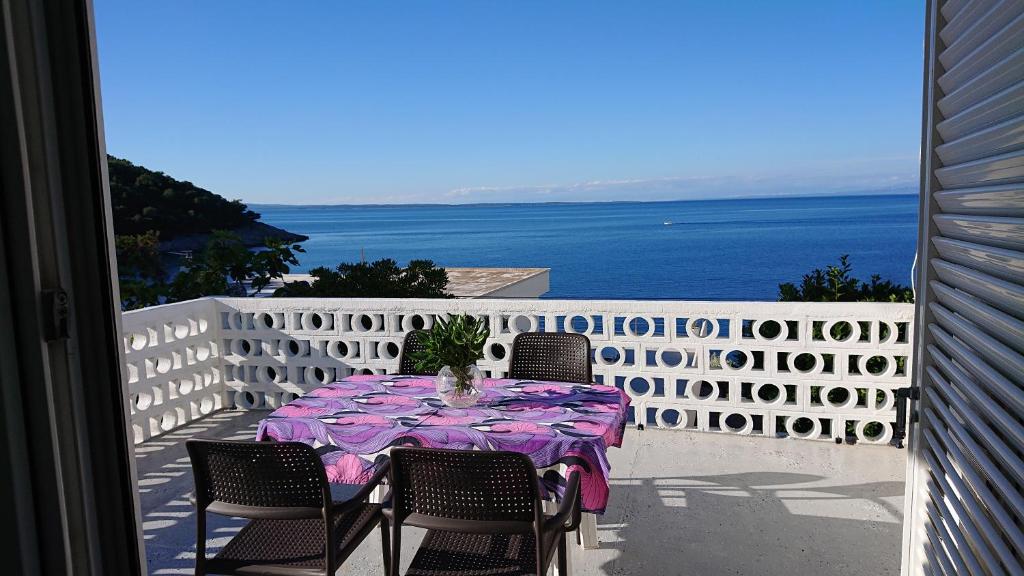 a table on a balcony with a view of the ocean at Apartmani Antonieta in Veli Lošinj