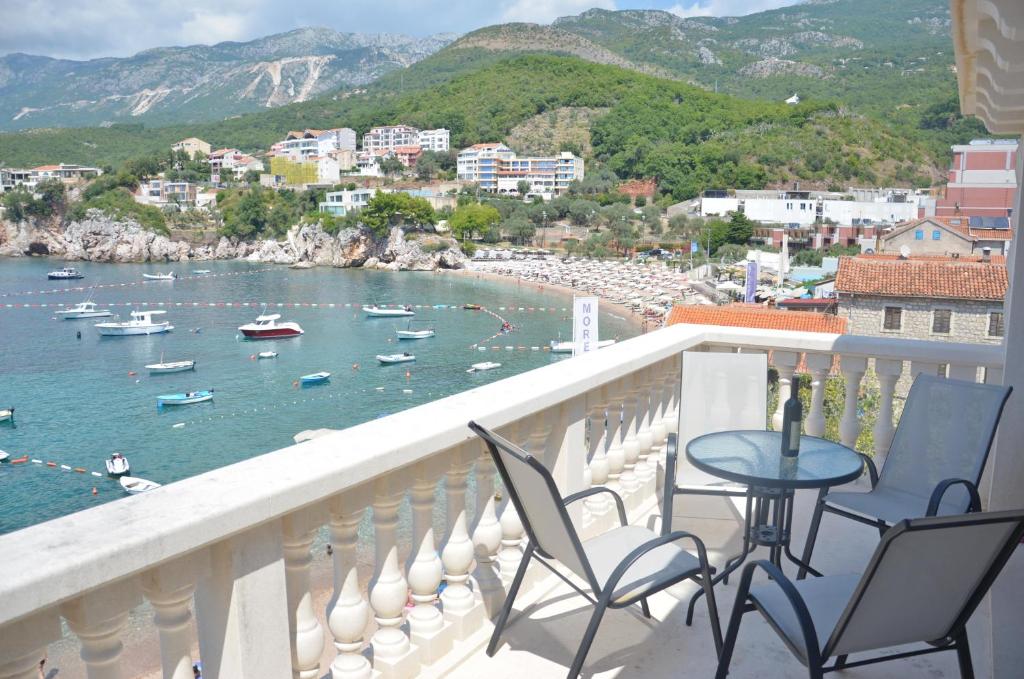 einen Balkon mit Stühlen und einem Tisch und Booten im Wasser in der Unterkunft Andaluni Beach Apartments in Pržno