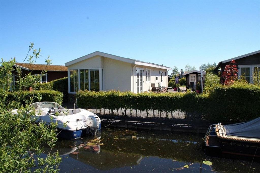 a boat is parked in front of a house at Resort Venetie Chalet nr.42 in Giethoorn