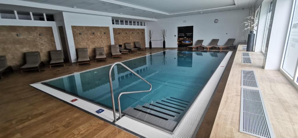 a large swimming pool in a room with chairs at Moser Apartment Carlsbad in Karlovy Vary