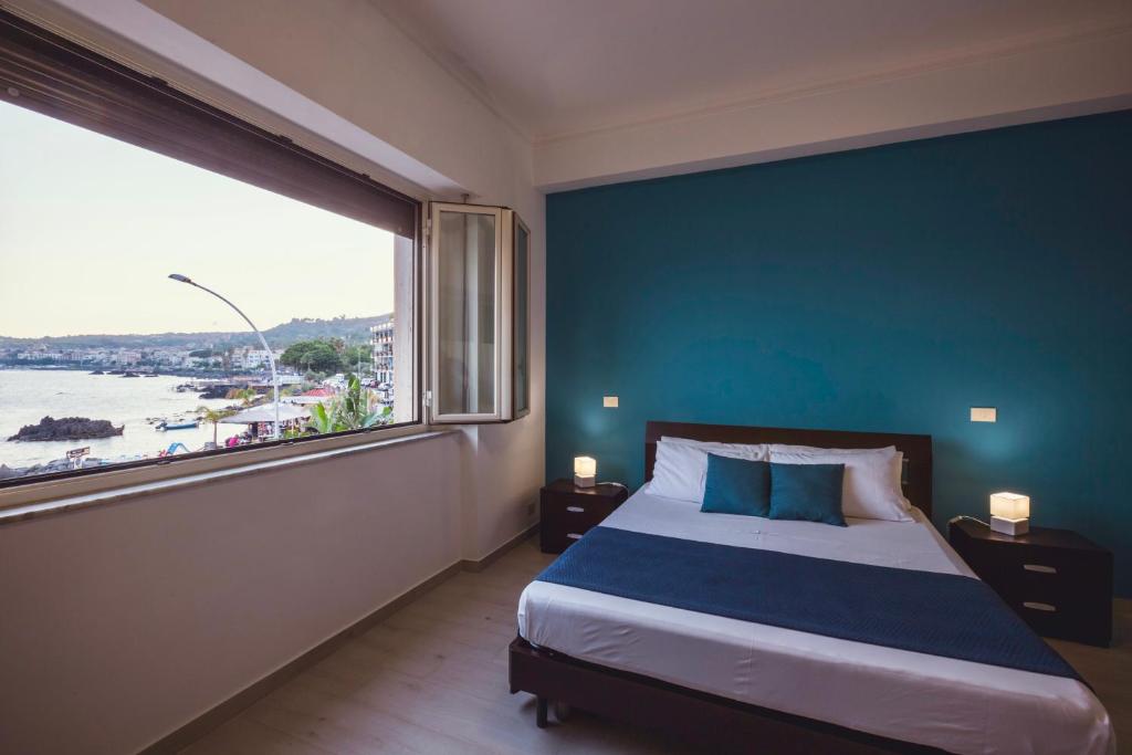 a bedroom with a blue wall and a bed with a large window at Oasis in Acitrezza