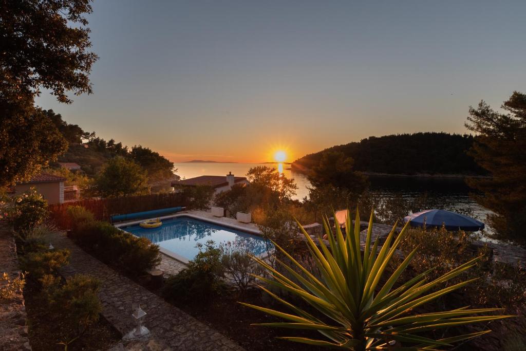 a swimming pool with the sunset in the background at Villa Goga in Vela Luka