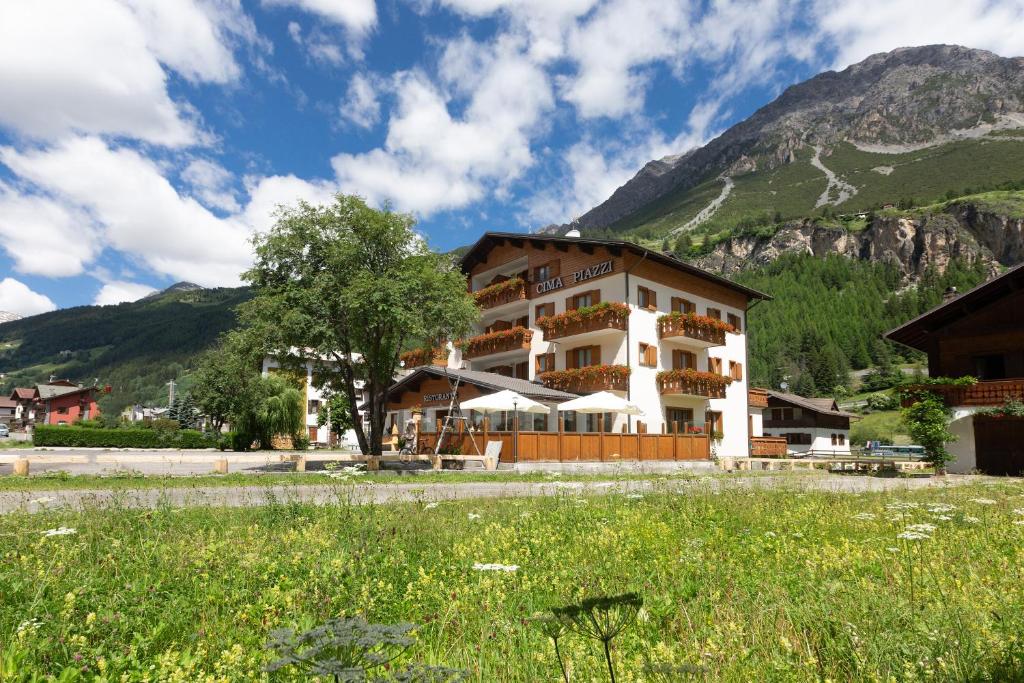 a large building with a mountain in the background at Hotel Cima Piazzi in Valdidentro