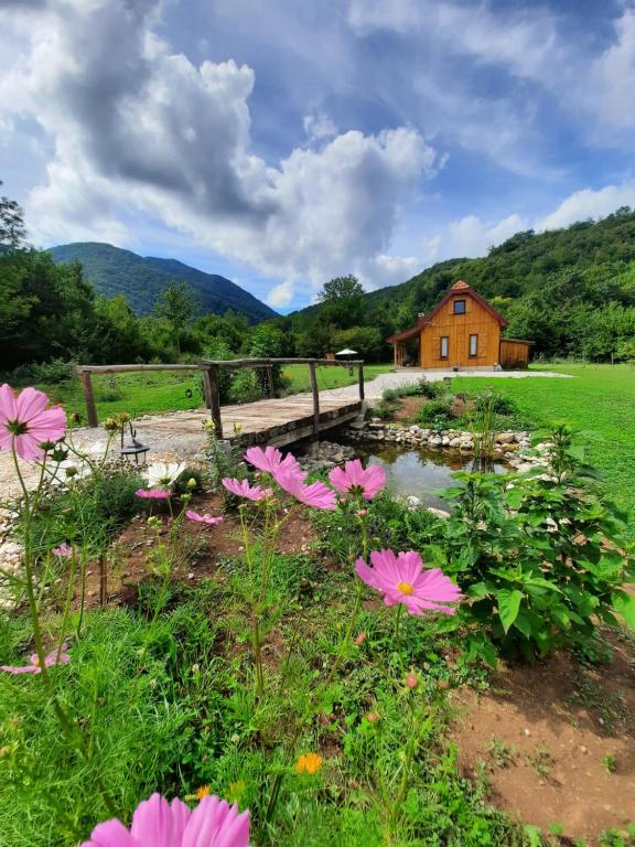 un giardino con fiori rosa e un ponte di legno di Spirit of Velebit a Gospić