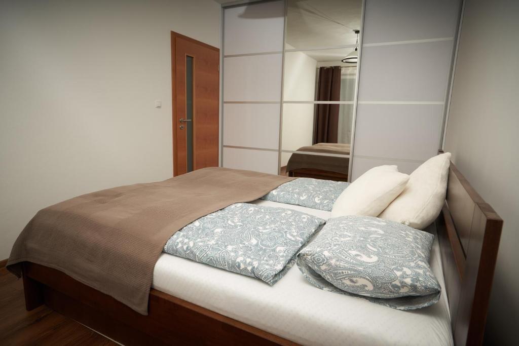 a bedroom with a bed with pillows and a mirror at Apartman A&M in Banská Bystrica