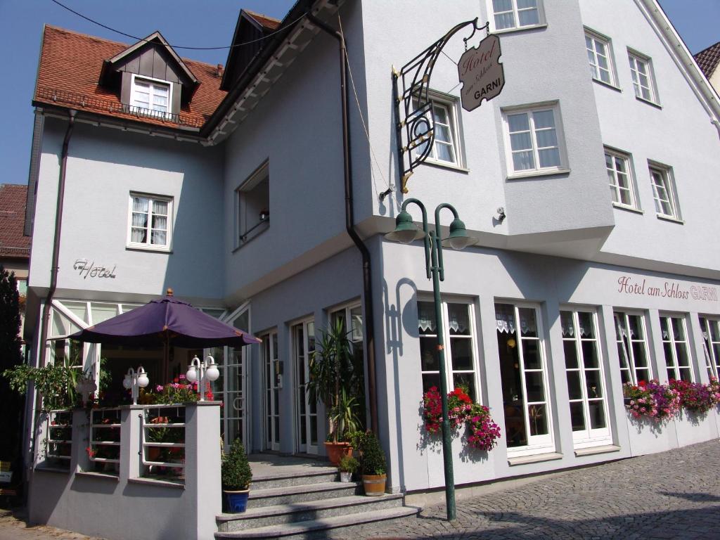 a white building with flowers in front of it at Hotel am Schloss Neuenstein in Neuenstein