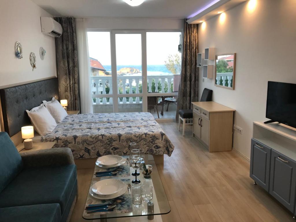 a hotel room with a bed and a couch and a table at Студио Сънрайз А28, Лозенец in Lozenets
