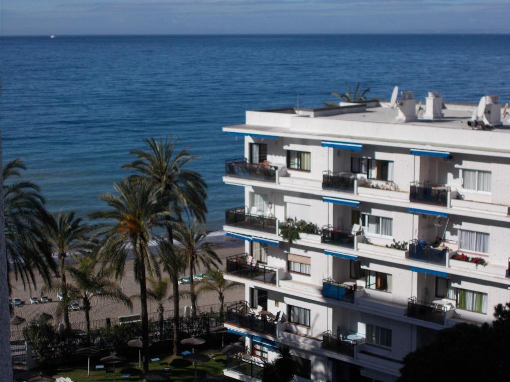 un edificio en la playa con palmeras y el océano en Skol 406A by Completely Marbella, en Marbella